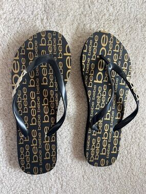 Bebe Black and Gold Logo Print Flip Flops